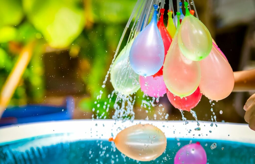 Water balloons filling near pool—fun things to do at home this summer.