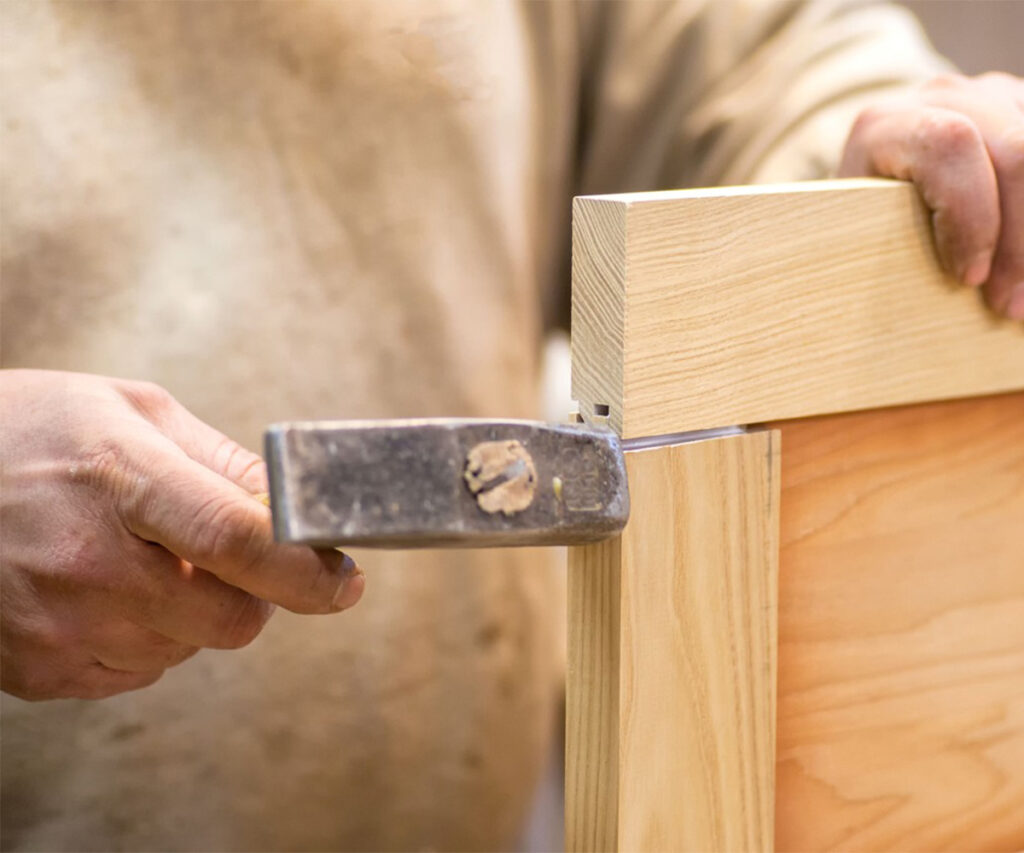 Close-up of mortise-and-tenon joint tapped into place on a solid wood frame.