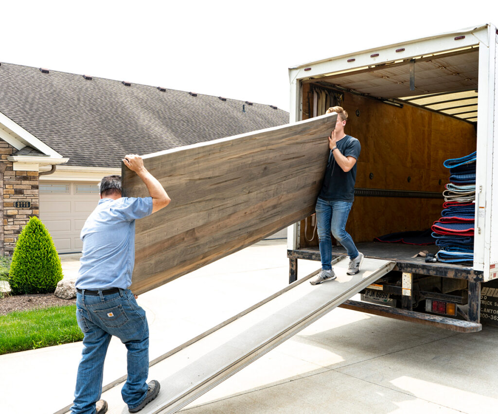 Furniture delivery team unloading large wood table