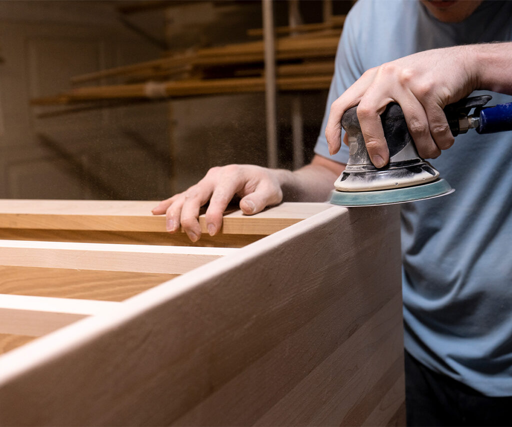 Sanding hardwood panel during custom furniture production